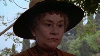 Movie still from “Enchanted April” (1991), directed by Mike Newell – An older woman wearing a brown hat and a brown dress; Close Up shot, High angle