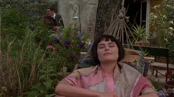 Movie still from “Enchanted April” (1991), directed by Mike Newell – A woman is sitting in a chair in a garden with her eyes closed; Medium shot, High angle