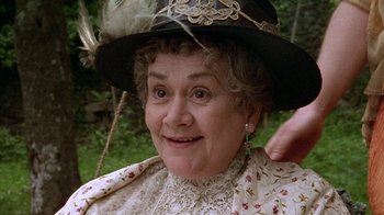 Movie still from “Enchanted April” (1991), directed by Mike Newell – An older woman wearing a black hat and a white dress; Close Up shot, High angle