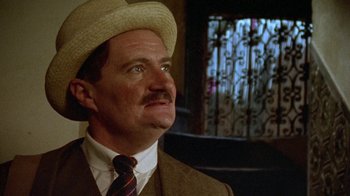 Movie still from “Enchanted April” (1991), directed by Mike Newell – A person wearing a hat and a suit; Close Up shot, Low angle