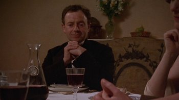 Movie still from “Enchanted April” (1991), directed by Mike Newell – A man sitting at a table with a glass of red wine in front of him; Close Up shot, Over the shoulder angle