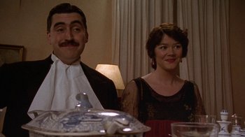 Movie still from “Enchanted April” (1991), directed by Mike Newell – A man and a woman sitting at a dinner table; Medium shot, Low angle