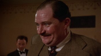 Movie still from “Enchanted April” (1991), directed by Mike Newell – A person wearing a suit and a tie; Close Up shot, Low angle