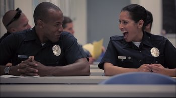 Movie still from “End of Watch” (2012), directed by David Ayer – Two police officers are sitting at a table talking to each other; Medium shot, Over the shoulder angle