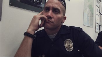 Movie still from “End of Watch” (2012), directed by David Ayer – A man in a police officer's uniform with his chin resting on his hand; Close Up shot, Over the shoulder angle