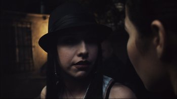 Movie still from “End of Watch” (2012), directed by David Ayer – A woman wearing a black hat looking at the camera; Close Up shot, Over the shoulder angle