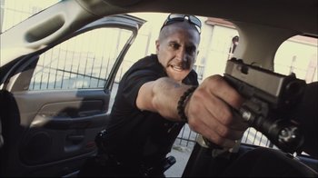 Movie still from “End of Watch” (2012), directed by David Ayer – A police officer holding a gun in a car; Medium shot, Low angle