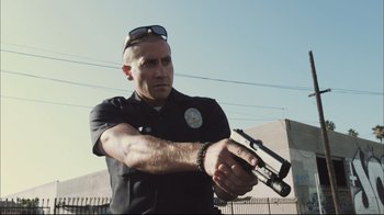 Movie still from “End of Watch” (2012), directed by David Ayer – A police officer holding a gun in his hands; Medium shot, Low angle