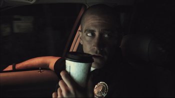Movie still from “End of Watch” (2012), directed by David Ayer – A police officer is drinking coffee in his car; Close Up shot, Over the shoulder angle