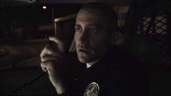 Movie still from “End of Watch” (2012), directed by David Ayer – A police officer sitting in the back of a car at night; Close Up shot, Over the shoulder angle