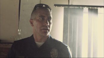 Movie still from “End of Watch” (2012), directed by David Ayer – A police officer is looking out a window; Close Up shot, Over the shoulder angle