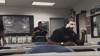 Movie still from “End of Watch” (2012), directed by David Ayer – Two police officers sitting in a room with papers on their faces; Medium shot, Over the shoulder angle