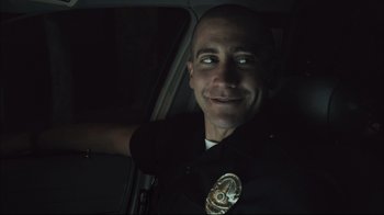 Movie still from “End of Watch” (2012), directed by David Ayer – A man in a police uniform sitting in a car; Close Up shot, Over the shoulder angle