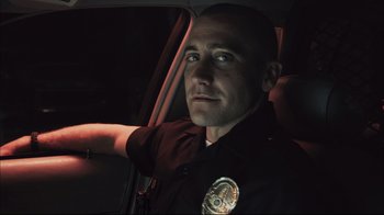 Movie still from “End of Watch” (2012), directed by David Ayer – A police officer sitting in the back of a car at night; Close Up shot, Low angle