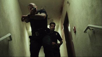 Movie still from “End of Watch” (2012), directed by David Ayer – Two police officers standing next to each other in a hallway; Medium shot, Low angle