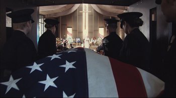 Movie still from “End of Watch” (2012), directed by David Ayer – A group of people standing next to an american flag draped casket; Wide shot, High angle