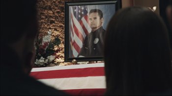 Movie still from “End of Watch” (2012), directed by David Ayer – A picture of a police officer is shown in front of a flag; Close Up shot, Over the shoulder angle