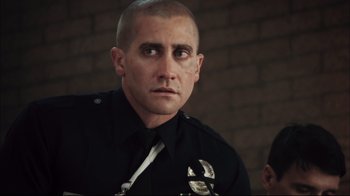 Movie still from “End of Watch” (2012), directed by David Ayer – A police officer looking into the distance with a serious look on his face; Close Up shot, Over the shoulder angle