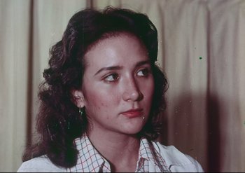 Movie still from “Enforcer from Death Row” (1976), directed by Efren C. Piñon – A young woman with long dark curly hair wearing a checkered shirt; Close Up shot, Low angle