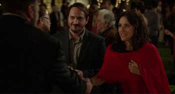 Movie still from “Enough Said” (2013), directed by Nicole Holofcener – A man and a woman shaking hands at a party; Medium shot, Over the shoulder angle