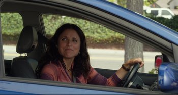 Movie still from “Enough Said” (2013), directed by Nicole Holofcener – A woman sitting in the driver's seat of a blue car; Medium shot, Over the shoulder angle