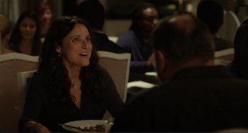 Movie still from “Enough Said” (2013), directed by Nicole Holofcener – A woman sitting at a table with a plate of food in front of a man; Medium shot, Over the shoulder angle