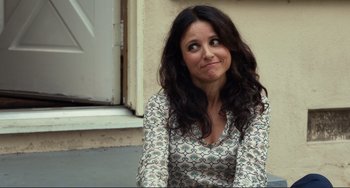 Movie still from “Enough Said” (2013), directed by Nicole Holofcener – A woman sitting on the ground with her mouth wide open; Close Up shot, Over the shoulder angle