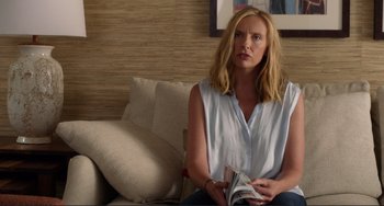 Movie still from “Enough Said” (2013), directed by Nicole Holofcener – A woman sitting on a couch holding a magazine; Medium shot, Over the shoulder angle
