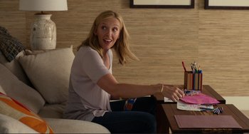 Movie still from “Enough Said” (2013), directed by Nicole Holofcener – A woman sitting on a couch in a living room; Medium shot, Over the shoulder angle
