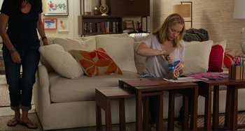 Movie still from “Enough Said” (2013), directed by Nicole Holofcener – A woman sitting at a table in a living room; Medium shot, High angle
