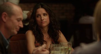 Movie still from “Enough Said” (2013), directed by Nicole Holofcener – A person sitting at a table; Close Up shot, Over the shoulder angle