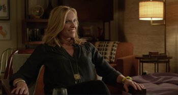 Movie still from “Enough Said” (2013), directed by Nicole Holofcener – A woman sitting in a chair with a glass of wine; Medium shot, Over the shoulder angle