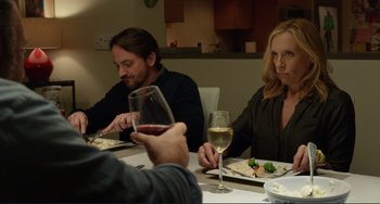 Movie still from “Enough Said” (2013), directed by Nicole Holofcener – A group of people sitting at a dinner table with wine glasses; Medium shot, Over the shoulder angle