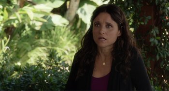 Movie still from “Enough Said” (2013), directed by Nicole Holofcener – A person wearing a jacket near a bush; Close Up shot, Over the shoulder angle