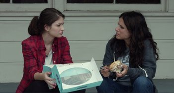 Movie still from “Enough Said” (2013), directed by Nicole Holofcener – Two women sitting next to each other holding a box of donuts; Close Up shot, Over the shoulder angle