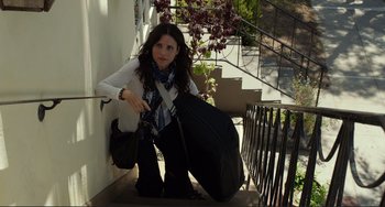 Movie still from “Enough Said” (2013), directed by Nicole Holofcener – A young woman kneeling down on the steps with her luggage; Wide shot, High angle