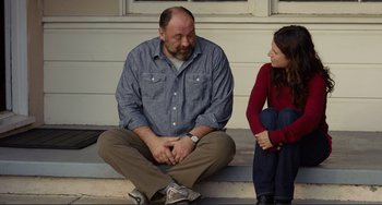 Movie still from “Enough Said” (2013), directed by Nicole Holofcener – A man and a woman sitting on the steps of a house; Medium shot, Over the shoulder angle