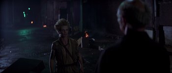 Movie still from “Escape from New York” (1981), directed by John Carpenter – A man in a yellow shirt is talking on a cell phone; Medium shot, Over the shoulder angle