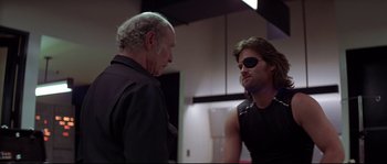 Movie still from “Escape from New York” (1981), directed by John Carpenter – A man in a black shirt is talking to another man in a black shirt; Close Up shot, Over the shoulder angle