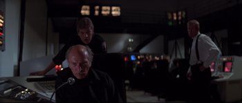 Movie still from “Escape from New York” (1981), directed by John Carpenter – A man sitting in a chair next to another man; Medium shot, Low angle