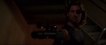 Movie still from “Escape from New York” (1981), directed by John Carpenter – A man holding a gun in a dark room; Close Up shot, Over the shoulder angle