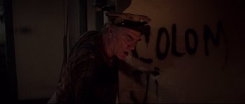 Movie still from “Escape from New York” (1981), directed by John Carpenter – An older man wearing a military hat in front of a wall with graffiti; Medium shot, Low angle