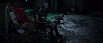 Movie still from “Escape from New York” (1981), directed by John Carpenter – A woman sitting on a chair holding a gun; Wide shot, High angle