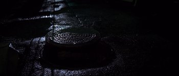 Movie still from “Escape from New York” (1981), directed by John Carpenter – A dark picture of a manhole cover in the dark; Extreme Close Up shot, Overhead angle