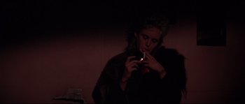 Movie still from “Escape from New York” (1981), directed by John Carpenter – A woman is smoking a cigarette in a dark room; Close Up shot, Low angle
