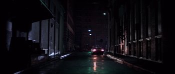 Movie still from “Escape from New York” (1981), directed by John Carpenter – A car is driving down a dark street at night; Extreme Wide shot, High angle