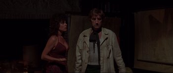 Movie still from “Escape from New York” (1981), directed by John Carpenter – A man and a woman standing next to each other in a dark room; Medium shot, Over the shoulder angle