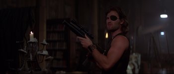 Movie still from “Escape from New York” (1981), directed by John Carpenter – A man in a black shirt holding a rifle; Medium shot, Low angle