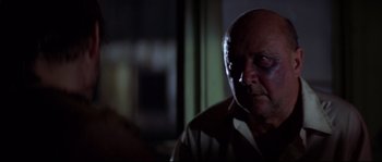Movie still from “Escape from New York” (1981), directed by John Carpenter – An older man with a bruised eye stares at the camera; Close Up shot, Over the shoulder angle