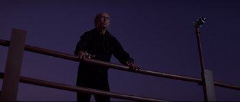 Movie still from “Escape from New York” (1981), directed by John Carpenter – An older man standing on a railing at night; Medium shot, Low angle